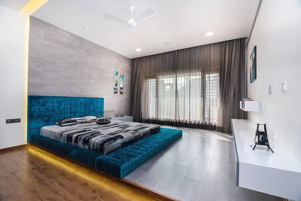 Chiếc giường ngủ thấp, có màu xanh cổ vịt nổi bật trong phòng ngủ của cậu con trai chủ nhà.