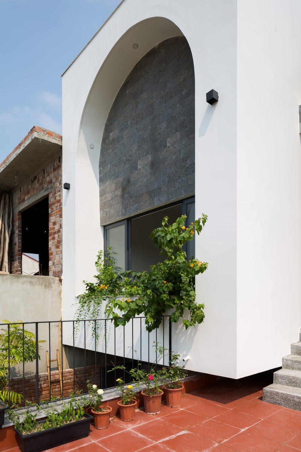 Sân trước khá rộng rãi để sàn bê tông tạo sự tương phản về màu sắc với không gian bên trong, đồng thời mang lại cảm giác mát lạnh, lạ mắt về ngôi nhà.