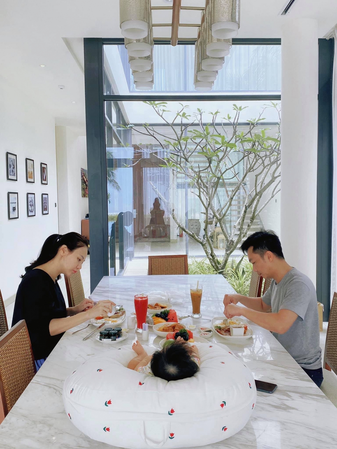 Ngôi nhà được trang trí chủ đạo với tông màu trắng, nâu và xen kẽ xanh. Khu vực bàn ăn thoáng đãng có thể nhìn ra ngoài nhờ những lớp cửa kính trong suốt.