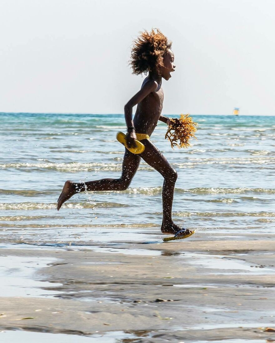 Cậu bé vui sướng chạy trên bãi biển ở Madagasca.