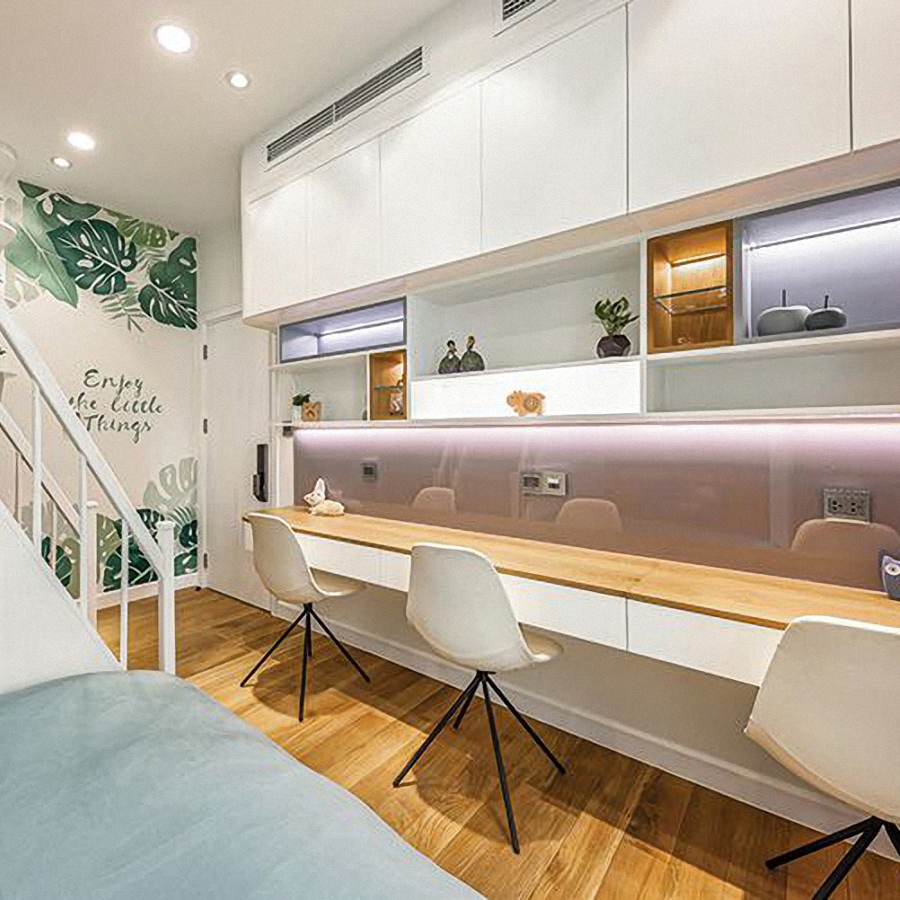 Trong phòng ngủ trẻ con chiếc bàn dài để học tập. Phía trên là tủ kệ kết hợp với hệ thống chiếu sáng trang trí.