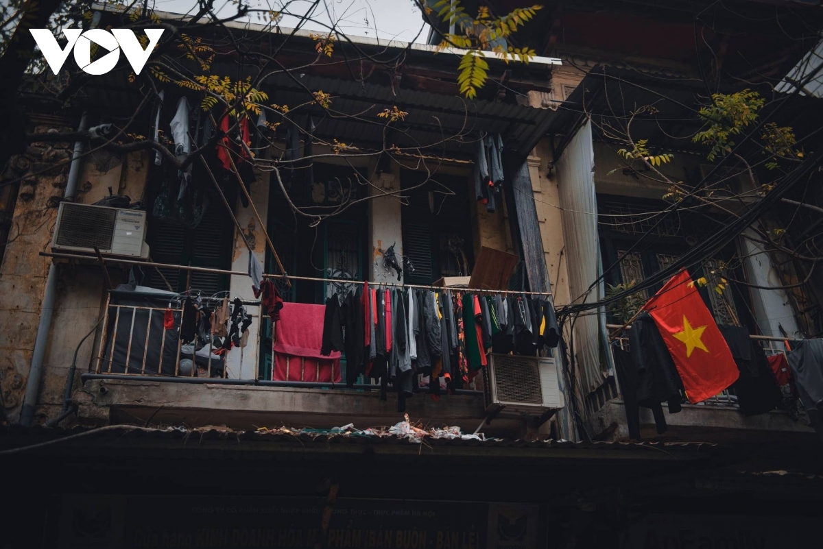 A national flag hangs in front of an old house, reminding people of the country’s traditions amid modern life.