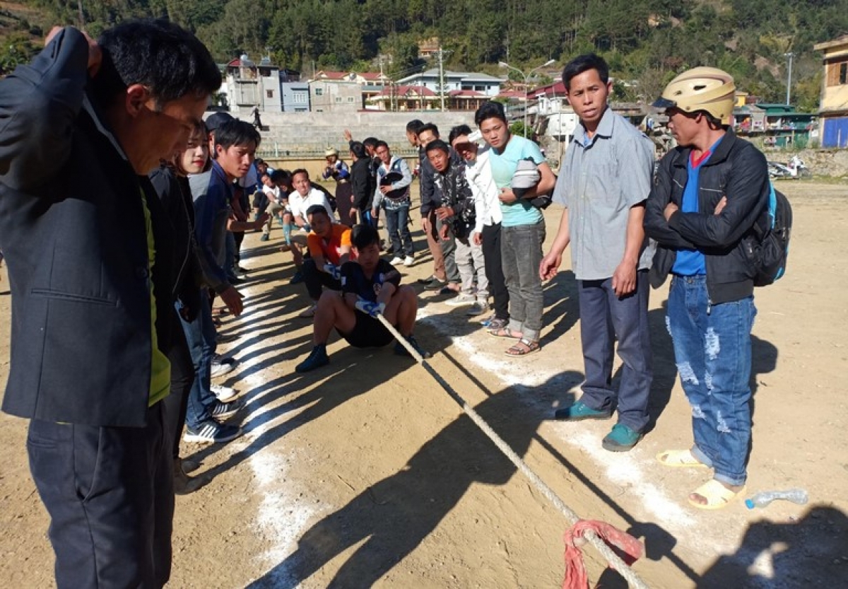 A tug-of-war competition sees participants cheered on by many supporters.