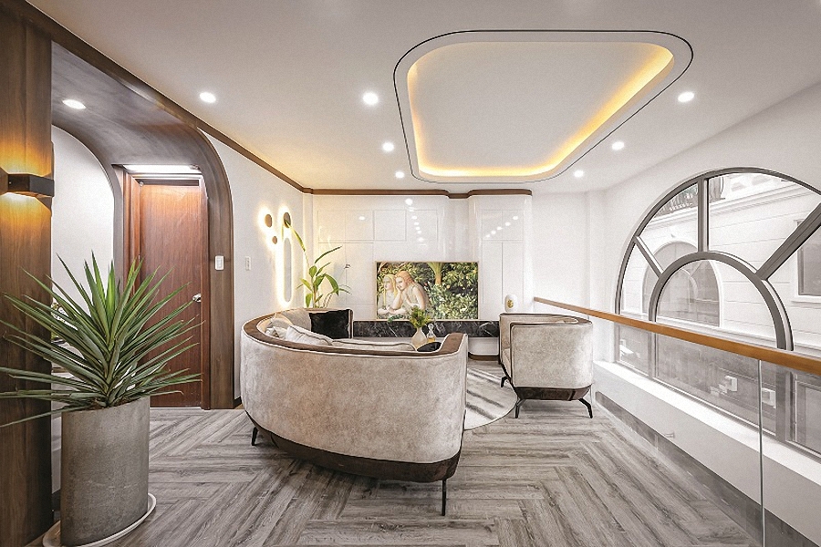 Vị trí đặt sofa kế bên khoảng thông tầng với ô cửa vòm lớn. Lan can kính góp phần mở rộng không gian và tăng cường chiếu sáng.