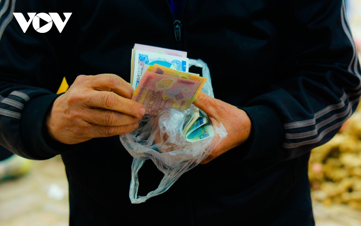 An elderly lady continues with her habit of wrapping money in a nilon bag, just like in the old times.