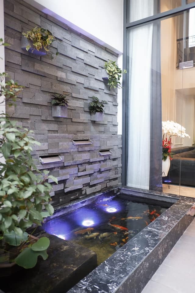 Ngôi nhà không xây hết diện tích mà chừa lại một khoảng rộng để làm mặt thoáng trước, thoáng sau. Phía trước, Bảo Anh xây bể cá, sử dụng đá ong ốp tường làm không gian thư giãn cho cả gia đình.