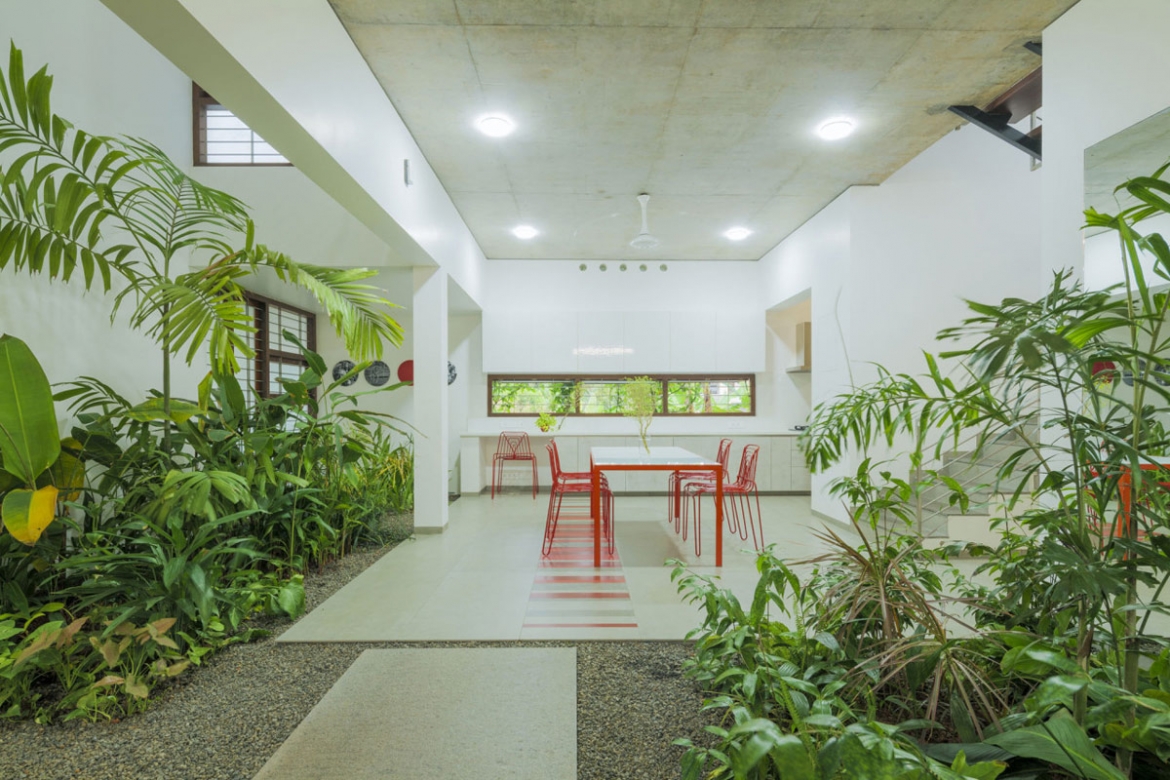 Đằng sau bộ bàn ăn là căn bếp hiện đại, với bức tường trải dài với cửa sổ, mở ra mặt sau của khu vườn.
