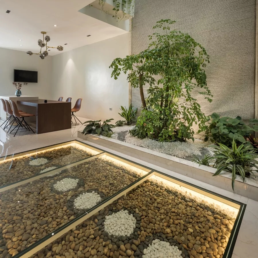Ngay dưới chân cầu thang là một thảm sỏi rộng 7,5 m2 được trải trên nền bê tông và phủ kính cường lực dày 15mm. Kế đó là một khu tiểu cảnh rộng 6m2 với cây hạnh phúc cao 2,5m, tượng trưng cho tình cảm của đôi vợ chồng trẻ sắp cưới.