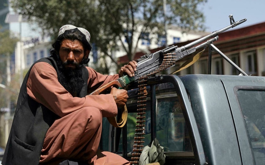 Chiến binh Hồi giáo Taliban cùng súng máy gắn trên xe bán tải cạnh phủ tổng thống Afghanistan vào tháng 8/2021. Ảnh: AP.