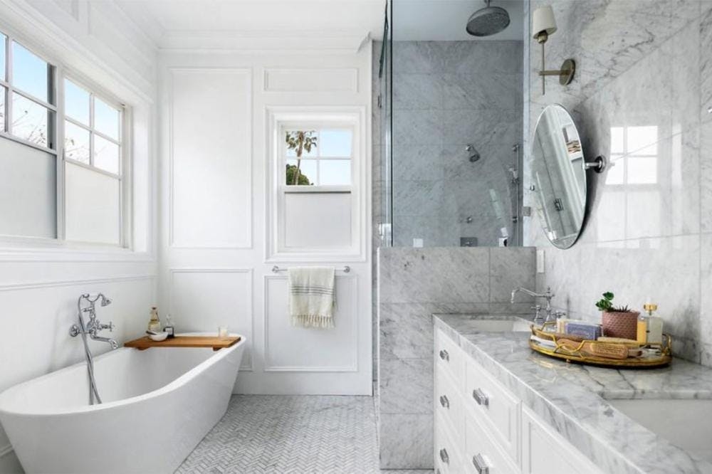 Phòng tắm được phủ bằng đá cẩm thạch Carrara và tủ màu trắng mang đến sự rung cảm hiện đại cho căn nhà.