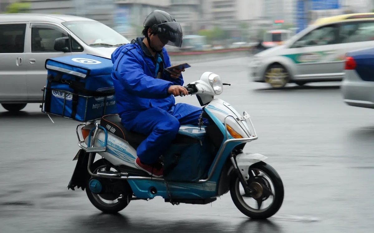 Một shipper giao hàng bằng xe đạp điện ở Trung Quốc thời Covid-19. Ảnh: AFP.