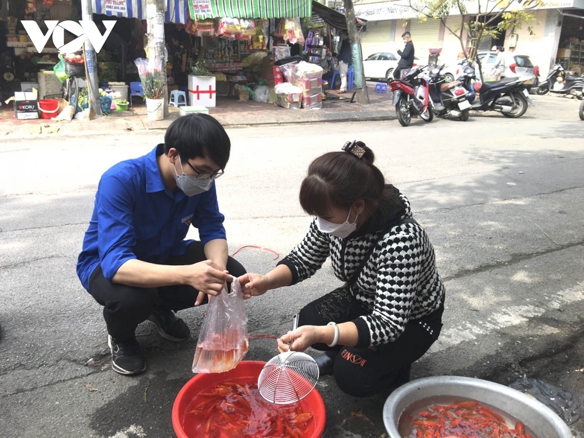 A volunteer assists a COVID-19 positive family to buy carp as they hold a farewell ceremony for the Kitchen Gods.