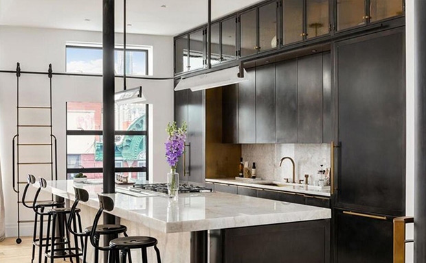 Nhà bếp không gian mở có bàn được thiết kế bằng thạch anh trắng, tủ sắt và đồ đạc bằng đồng.