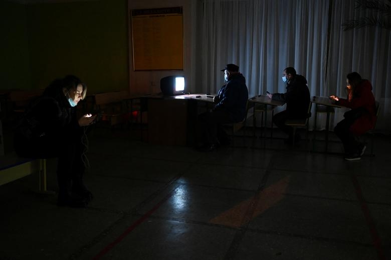 Người dân sử dụng thiết bị điện tử trong một hầm trú ẩn tối tăm ở Kiev, Ukraine. (Ảnh: Reuters)