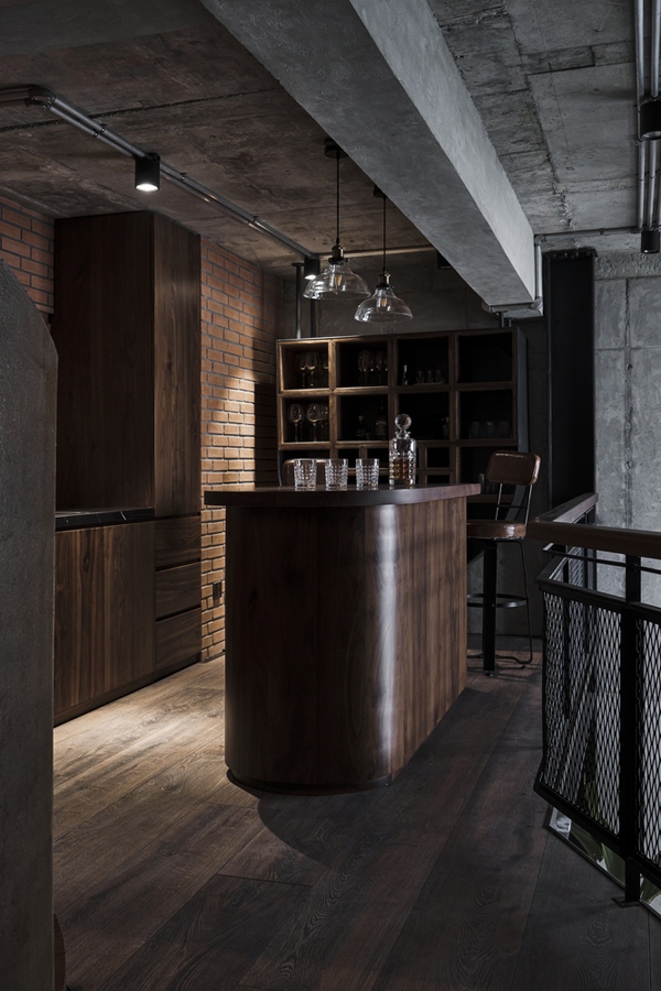 Quầy mini bar trên gác là nơi thư giãn của chủ nhân. Đồ nội thất gỗ màu sẫm cùng với các loại vật liệu thô mộc cho một chất cảm thâm trầm và ấn tượng