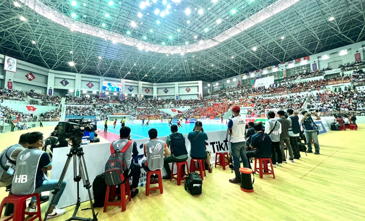 Phóng viên Ngọc Duy (đeo ba lô) và phóng viên Dương Thuật tác nghiệp trận đấu giữa ĐT Futsal Việt Nam với ĐT Futsal Thái Lan ở nhà thi đấu đa năng tỉnh Hà Nam.