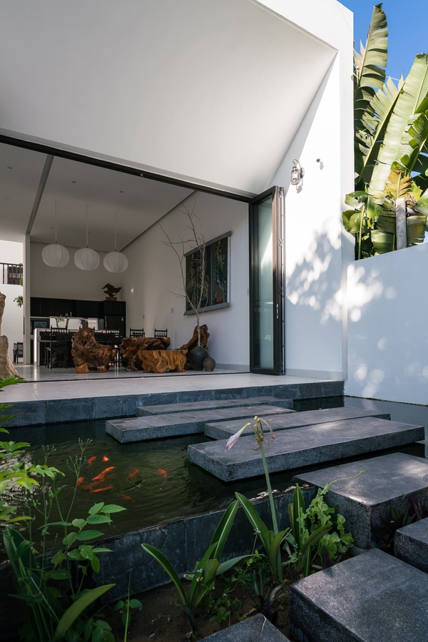 Lối vào phòng khách là những bậc đá đi trên mặt nước. Đây là một bể cá koi, vừa tạo cảnh quan vừa làm mát mẻ không gian.