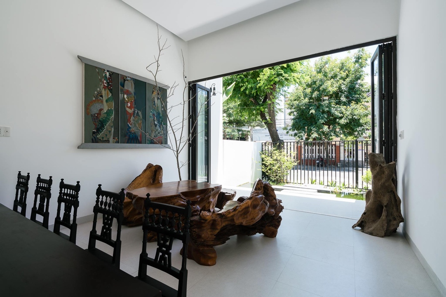Phòng khách nhìn ra con phố nhỏ phía trước với nhiều cây xanh. Bộ bàn ghế tiếp khách sử dụng những gốc cây tự nhiên tạo hình nghệ thuật. Nội thất khá chắt lọc và giản dị, tinh tế.