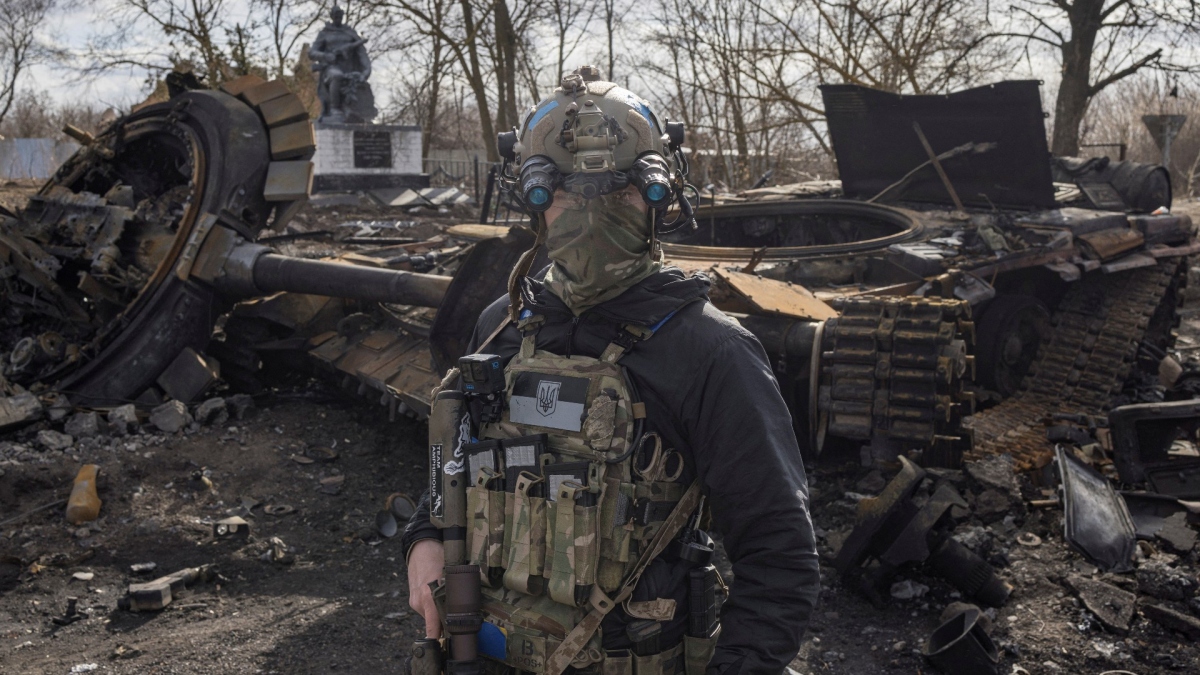 Binh sĩ Ukraine kế bên xác xe tăng bị phá hủy ở ngoại ô Kiev. Ảnh: Reuters