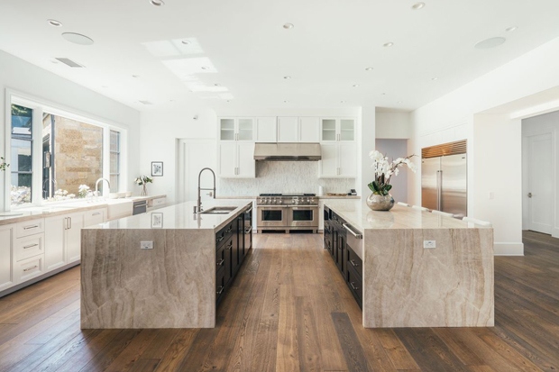 Khu vực bếp với mặt bàn bằng đá màu cát và sàn gỗ ván rộng duy trì bảng màu trung tính của ngôi nhà California.