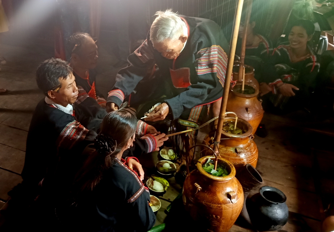 Thầy cúng cài lông gà, đeo vòng đồng, chuỗi hạt cườm cho những người được kết nghĩa.