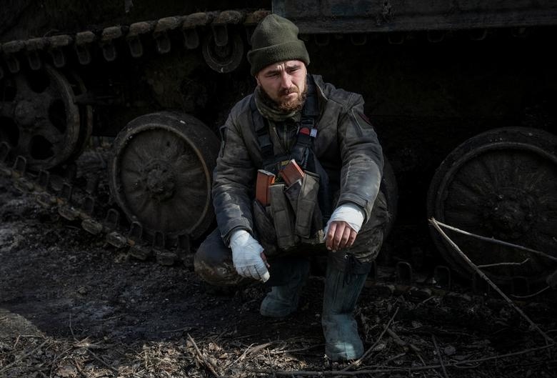 Binh sỹ Ukraine bị thương ngồi gần xe bọc thép bánh xích ở Bakhmut.
