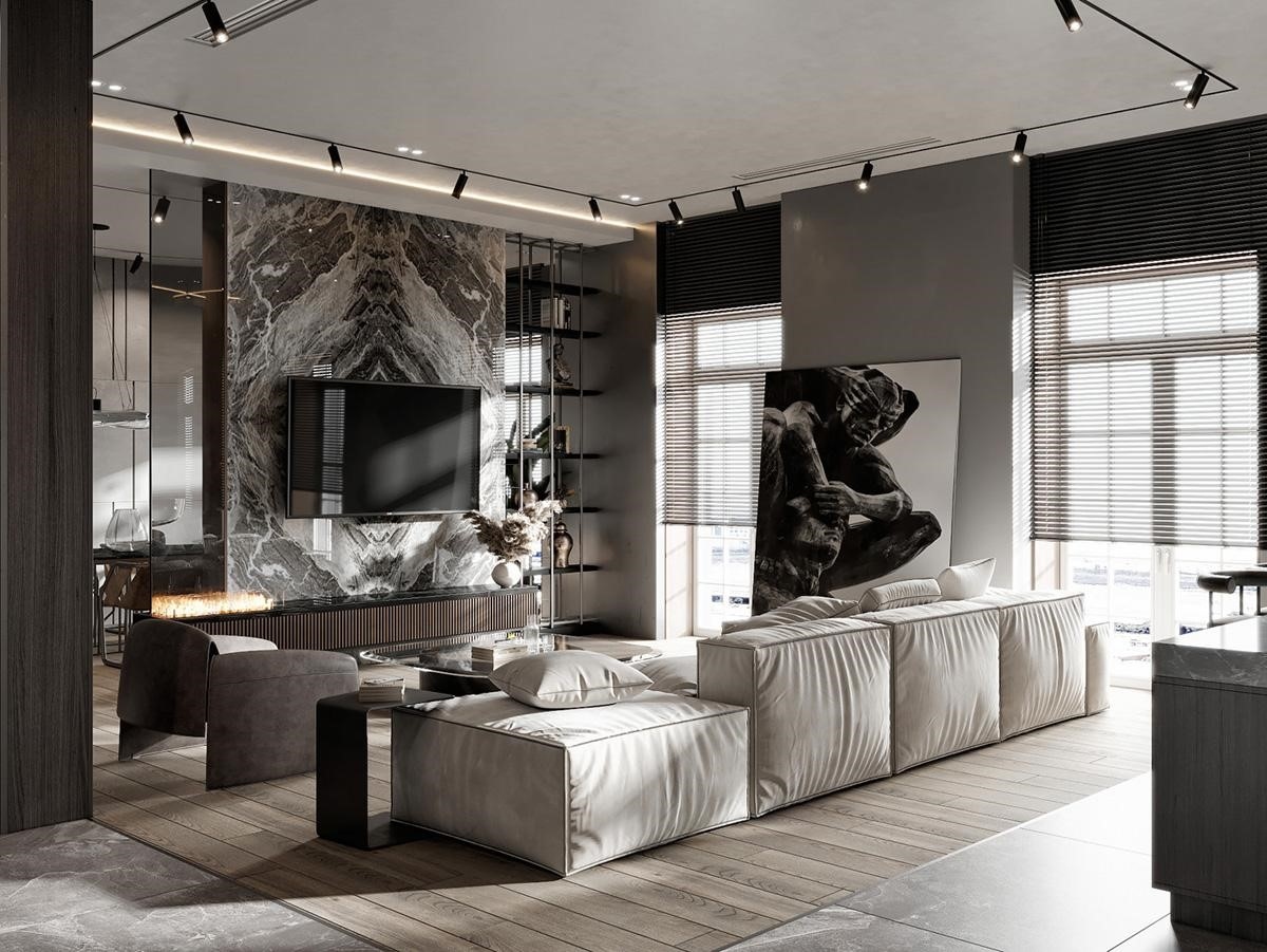 Bộ ghế sofa kiểu mô-đun màu nhạt phân chia phòng khách và bếp với không gian mở, cắt khu vực tiếp khách khỏi phòng ăn trong nhà. Tường TV sử dụng ốp đá cẩm thạch tạo điểm nhấn tuyệt đẹp, kết hợp cùng lớp gạch lát sàn giả gỗ tinh xảo.