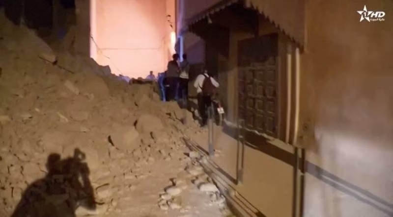 Người dân tại Marrakesh phải lách qua đống đổ nát để ra ngoài. Ảnh: Reuters