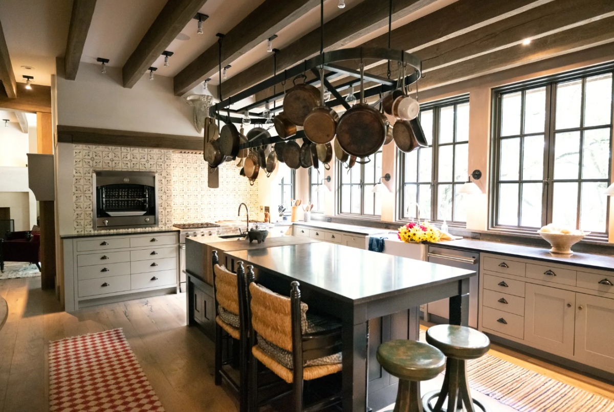 Phòng bếp được thiết kế theo phong cách đồng quê những bức tường màu trắng sữa. Thay vì sử dụng bàn đá cẩm thạch, căn phòng được trang trí với chất liệu gỗ, tạo cảm giác gần gũi với thiên nhiên. Căn phòng cũng bao gồm giá treo chảo, xoong, nồi trên trần nhà để giữ lại nét cổ điển vốn có.