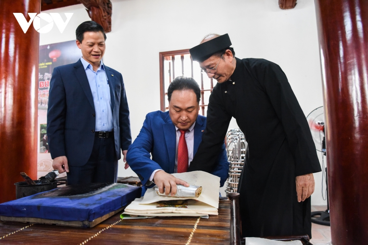 Phó Chủ tịch UBND tỉnh Vương Quốc Tuấn cùng nghệ nhân giới thiệu nghề làm tranh dân gian Đông Hồ tới bạn bè quốc tế