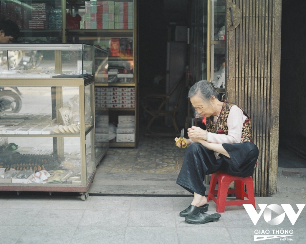 Cụ bà ngồi thư giãn trước cửa nhà trên phố Hàng Bạc
