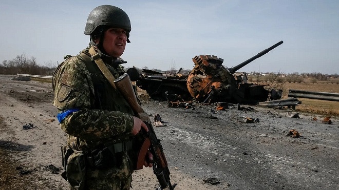 Binh sĩ Ukraine đứng gần một xe tăng của Nga bị phá hủy. Ảnh: Reuters
