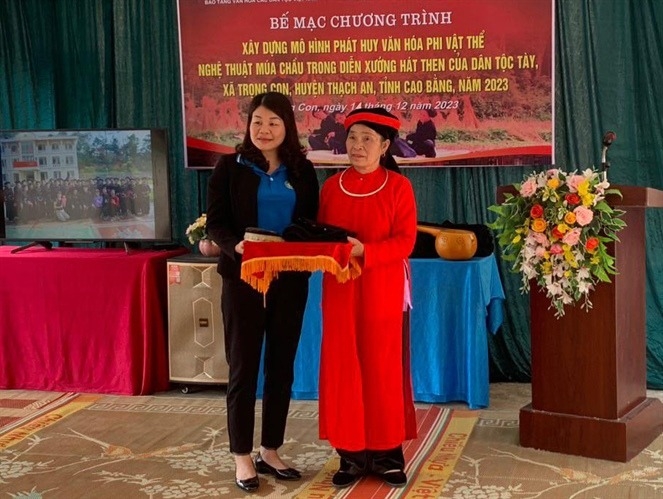 Nghệ nhân Ưu tú Nông Thị Nhít đón nhận trang phục, đạo cụ truyền thống do bà Tô Thị Thu Trang Giám đốc Bảo tàng văn hóa các dân tộc Việt Nam trao tặng phục vụ bảo tồn, phát huy di sản văn hóa phi vật thể dân tộc Tày