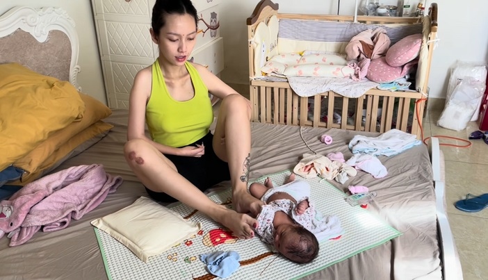 Bà mẹ Đà Lạt mặc quần áo cho con bằng chân thành thạo. (Ảnh cắt từ video)