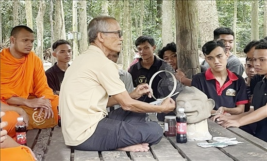 Nghệ nhân ưu tú Thạch Sang hướng dẫn học viên chế tác mão và mặt nạ. Ảnh: Thịnh Phúc