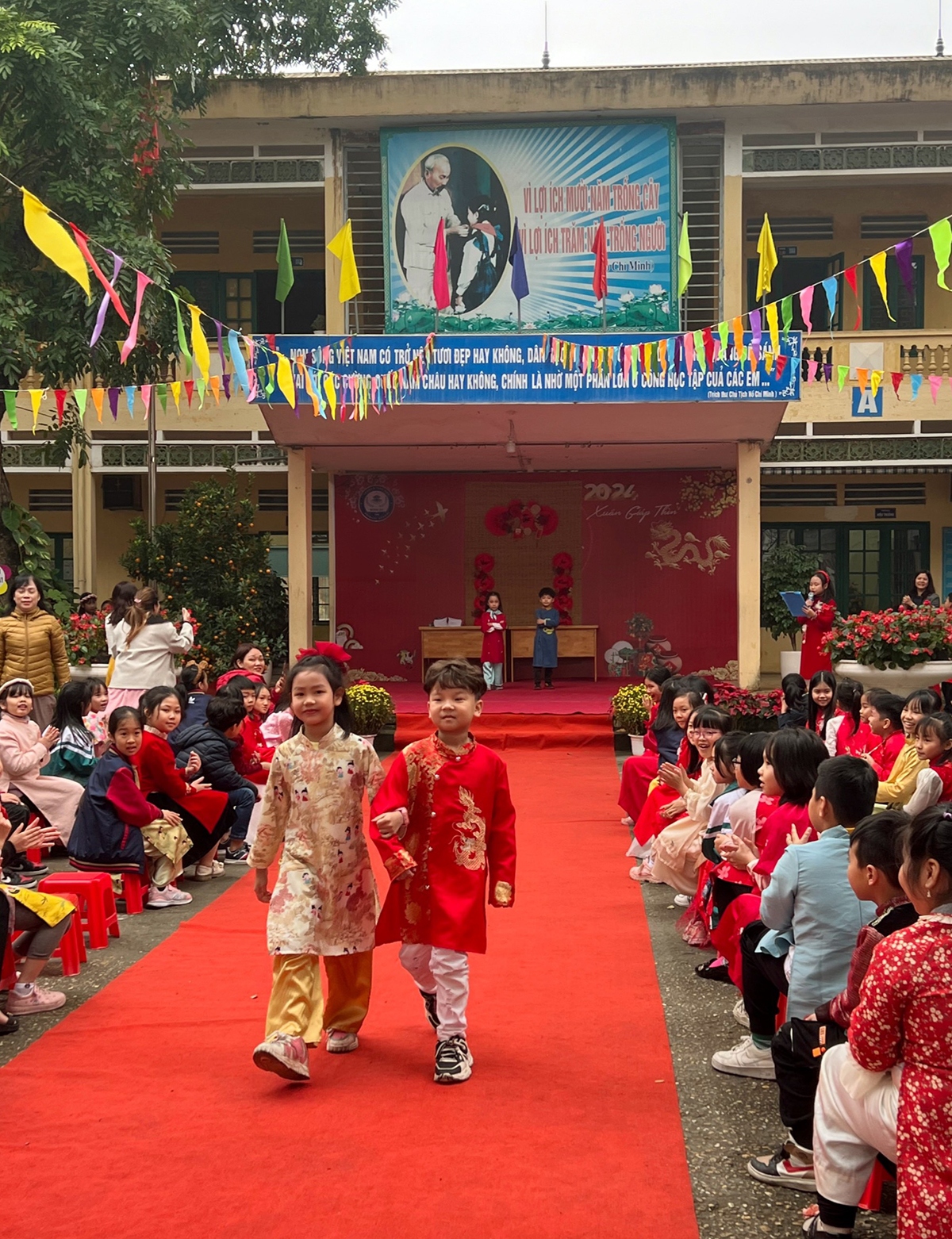 Từng cặp hai bạn nhỏ đi trên thảm đỏ để trình diễn áo dài.