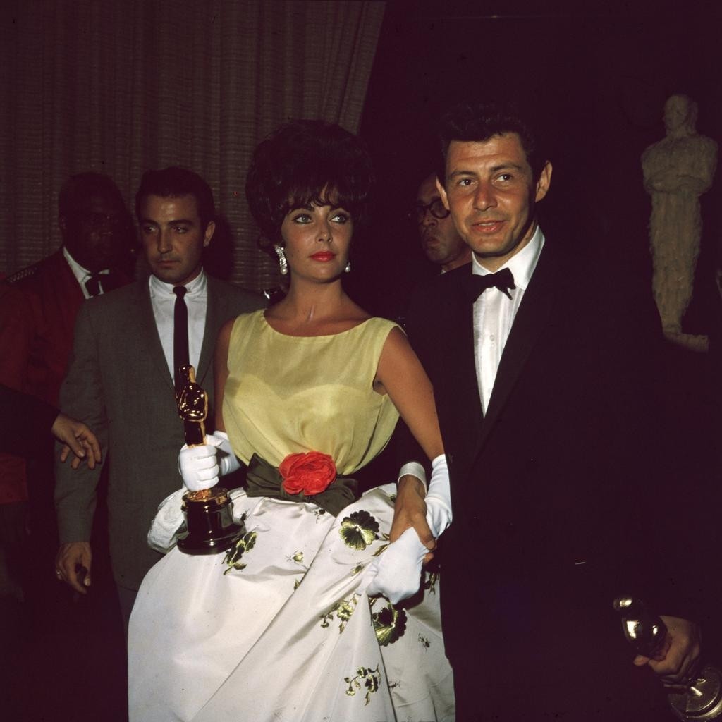 Chiến thắng đầu tiên của Elizabeth Taylor cho Nữ diễn viên chính xuất sắc nhất là vào năm 1961 với vai diễn Gloria Wandrous trong "Butterfield 8", kể về mối tình bi thảm của Gloria với một người Manhattanite giàu có tên là Weston Liggett, do Laurence Harvey thủ vai. Giống như mọi dịp khác, Elizabeth ăn mặc sang trọng, mặc một chiếc váy Dior hoa với các tông màu vàng nhạt, trắng và xanh lá cây, với một bông hoa màu san hô sáng gắn ở thắt lưng, từ Bộ sưu tập Haute Couture Xuân 1961 của nhà mốt, kim cương và khuyên tai mặt dây chuyền ngọc trai của Ruser và găng tay màu trắng dài đến khuỷu tay.
Tuy nhiên, chiếc váy này được một nhà đấu giá phát hiện trong một chiếc vali cũ ở London. Sau đó, nhà đấu giá Kerry Taylor Auctions đang tiến hành xử lý việc bán đấu giá chiếc váy cũng như những món đồ khác của Taylor. 