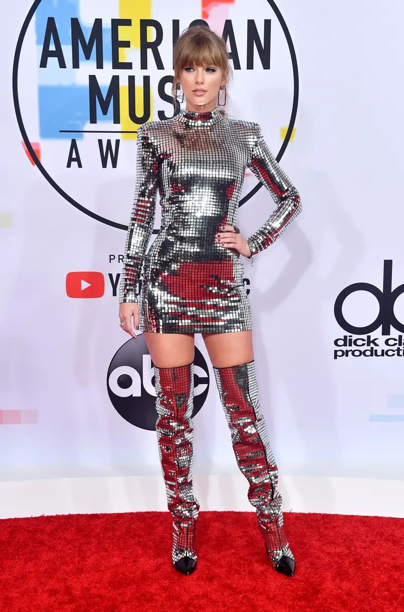 Taylor Swift tỏa sáng trong chiếc váy ngắn màu bạc tại Lễ trao giải Âm nhạc Mỹ 2018. Chiếc váy Balmain và đôi boots hiệu ứng disco được làm từ những tấm vải nhỏ màu bạc sáng bóng. (Ảnh: Getty)