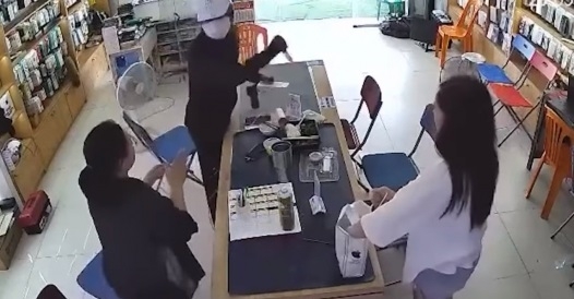 Đối tượng dùng hung khí khống chế nhân viên cửa hàng điện thoại. (Ảnh: Cắt từ camera)