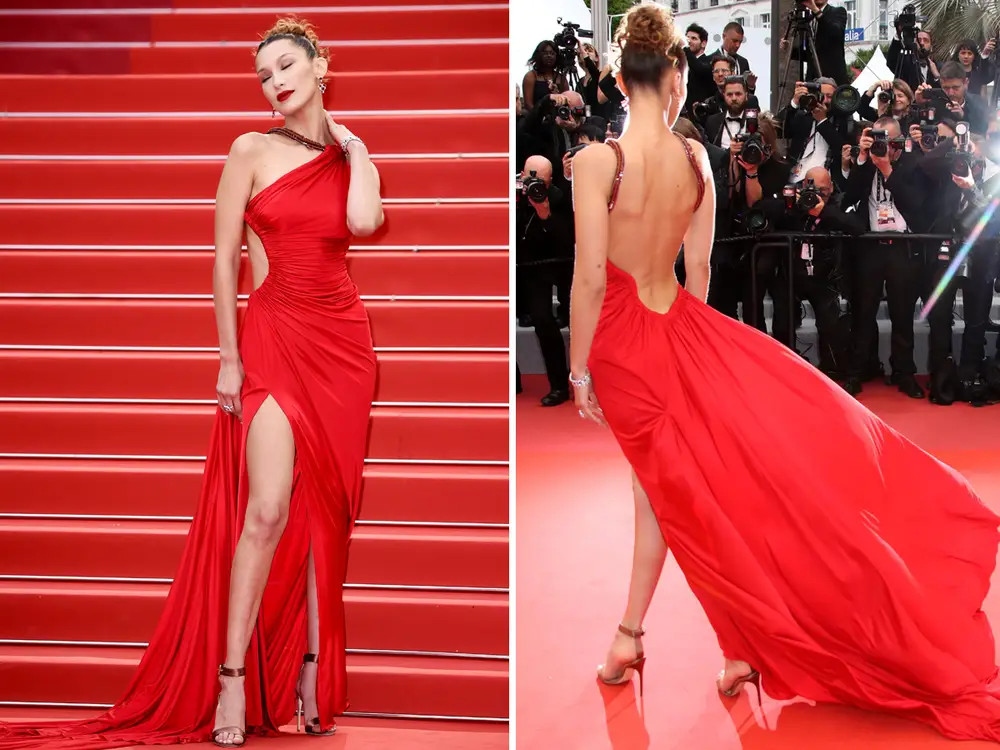 Trên thảm đỏ LHP Cannes 2019 ngày thứ tư, Bella Hadid thành tâm điểm chú ý với bộ váy dạ hội đỏ rực. Thiết kế xẻ tà cao, khoét hông giúp Bella khoe đôi chân dài, vóc dáng mảnh mai gợi cảm. Siêu mẫu 9x không cần ‘đồ nhỏ’ khi diện bộ cánh hở trọn lưng trần. Cô còn thường xuyên vén cao váy để vẻ ngoài càng thêm gợi cảm.