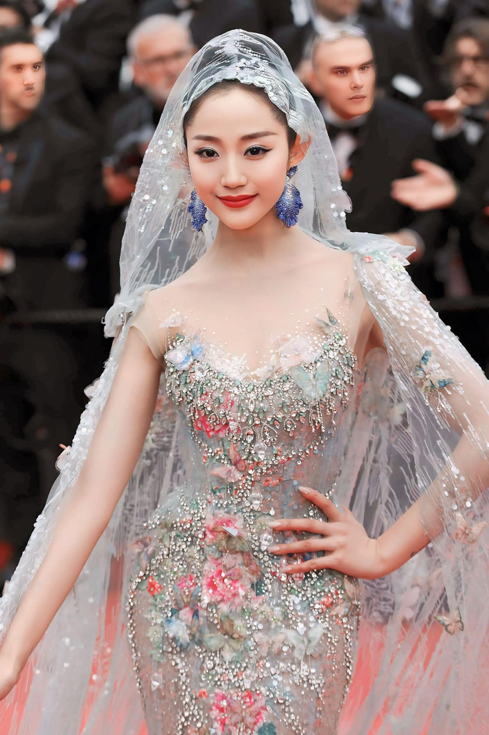 Nữ nhạc sĩ, diễn viên xứ Trung - Vạn Thiên Huệ xuất hiện nổi bật trên thảm đỏ Cannes năm nay với thiết kế tinh xảo của NTK Phạm Đặng Anh Thư. Bộ trang phục được lấy cảm hứng từ nét đẹp thi ca cổ điển, lãng mạn, với form dáng đuôi cá kết hợp voan đội đầu, tôn lên nhan sắc xinh đẹp của Vạn Thiên Huệ. Các chi tiết hoa, bươm bướm được điểm xuyết ở nhiều vị trí trên trang phục, tạo sự cân đối. Phụ kiện hoa tai, nhẫn độc đáo, nổi bật càng giúp Vạn Thiên Huệ trở thành tâm điểm chú ý trên thảm đỏ.