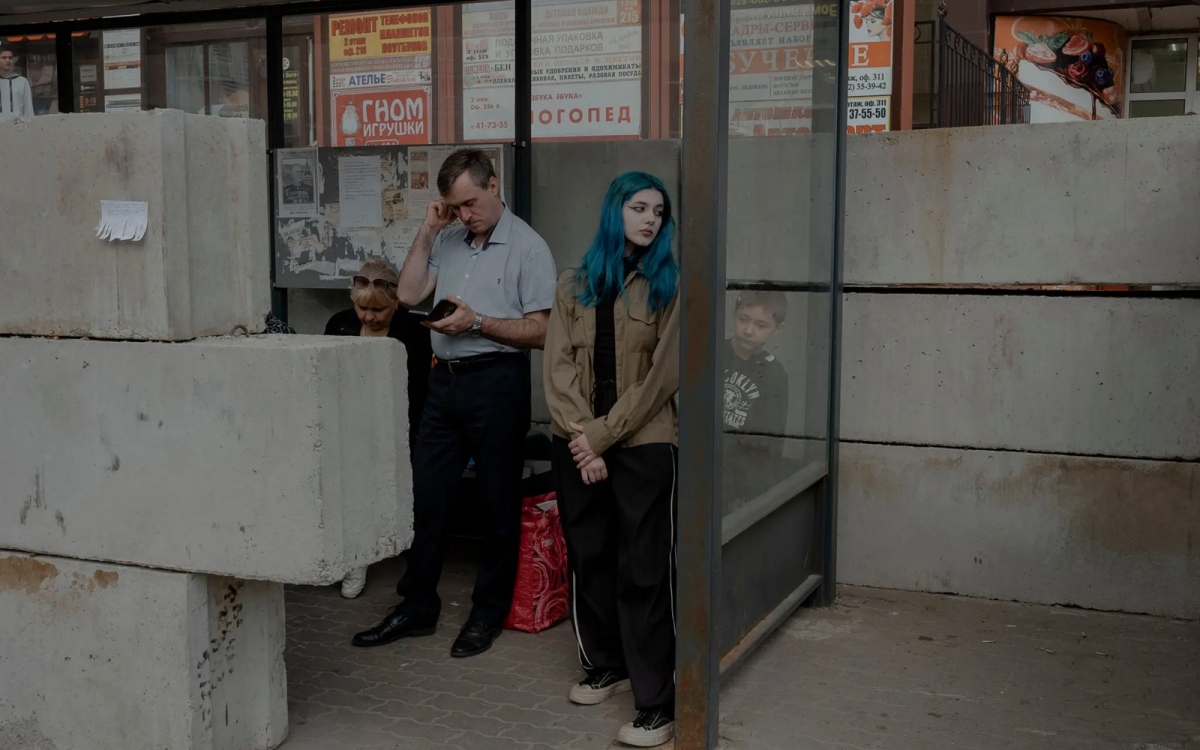 Alina (tóc xanh) trong điểm chờ xe buýt được gia cố bằng bê tông để chống đạn pháo. Ảnh: Nytimes.