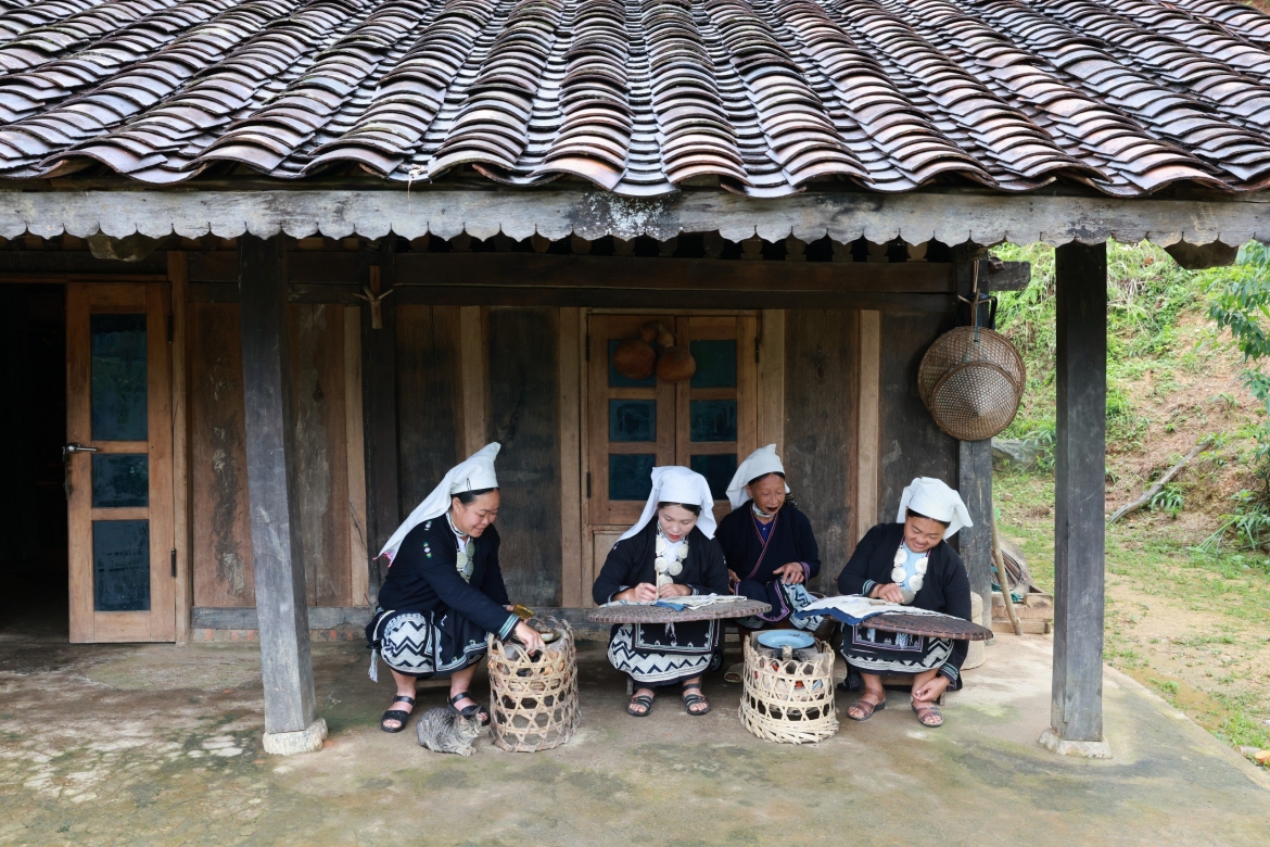 Chị Bàn Thị Liên (ngoài cùng bên trái) cùng các thành viên trong tổ thêu in hoa văn sáp ong xóm Hoài Khao. (Ảnh: Nhật Anh)