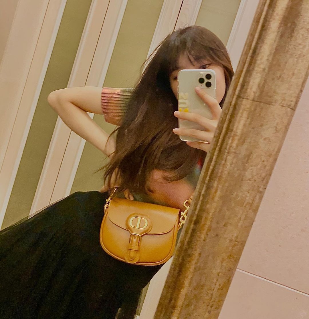 Túi đeo vai Dior Bobby là kiểu túi được thiết kế dáng tròn hiện đại với logo CD kim loại màu vàng gold, cùng với hiệu ứng khóa vintage vô cùng tinh tế. Thiết kế của chiếc túi này mang những đương nét cầu kỳ nhưng vẫn rất hài hòa. Tất cả tạo nên tổng thể mềm mại, nữ tính nhưng rất hiện đại. Đó chính là lý do tại sao nữ diễn viên yêu thích phong cách nhẹ nhàng như Suzy lại lựa chọn chiếc túi này. Dior Bobby có giá khoảng 3.500 USD.