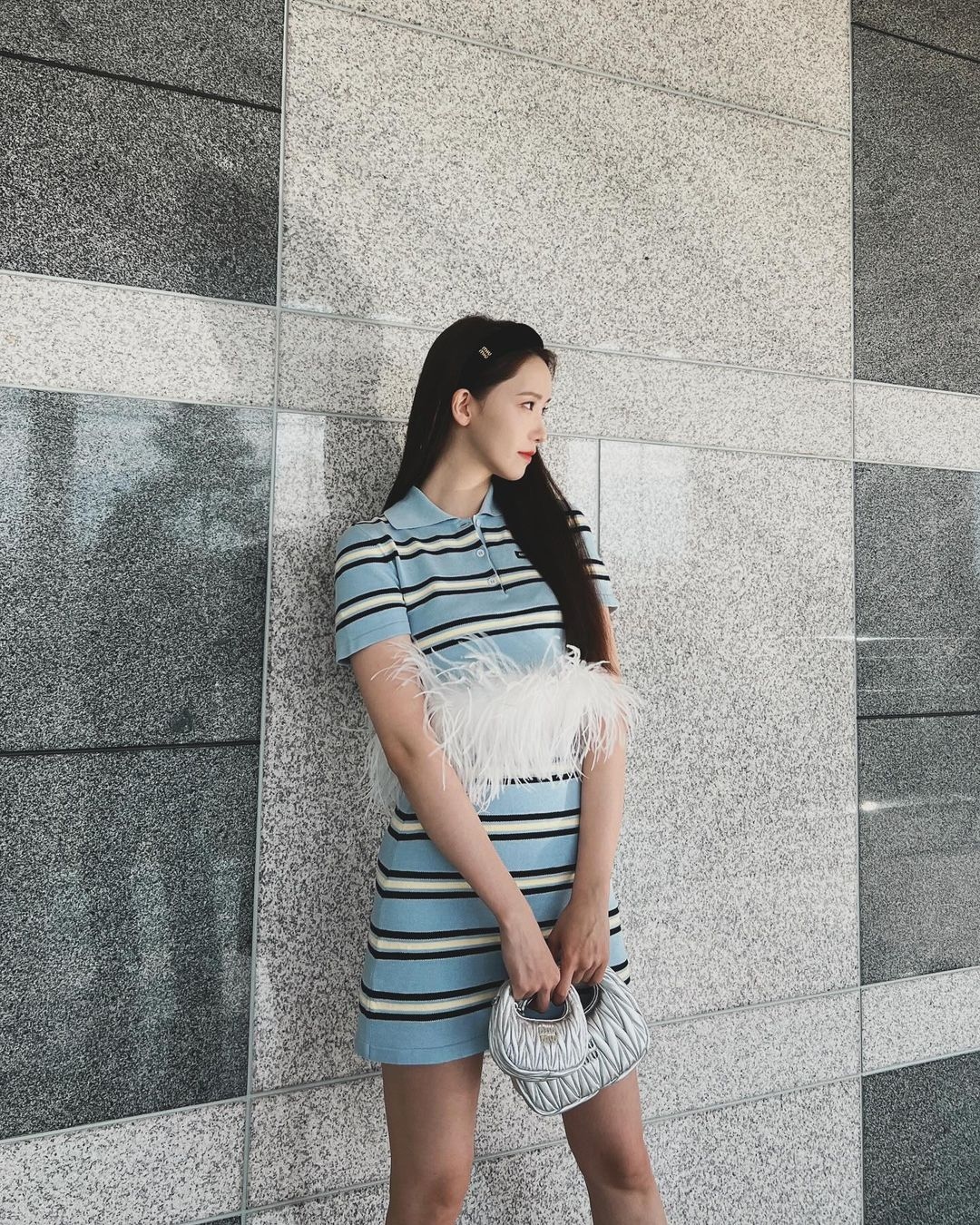 Yoona trở nên điệu đà, nữ tính hơn khi xách chiếc túi Miu Miu Wander Matelassé Nappa Leather Hobo. Cô nàng khoác một chiếc túi Miu Miu màu bạc kết hợp cùng váy có họa tiết độc đáo. Chiếc túi nữ ca sĩ mang theo là một trong những thiết kế mới nhất của Miu Miu, có giá khoảng 2.950 USD.