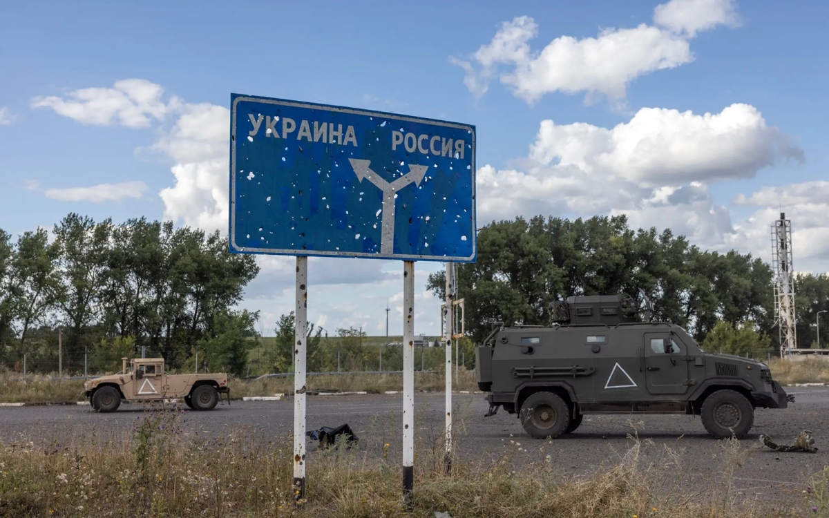 Xe quân sự Ukraine đi qua một chốt biên phòng Nga, nơi có biển chỉ đường (Ukraine bên trái, Nga bên phải). Ảnh: Nytimes.