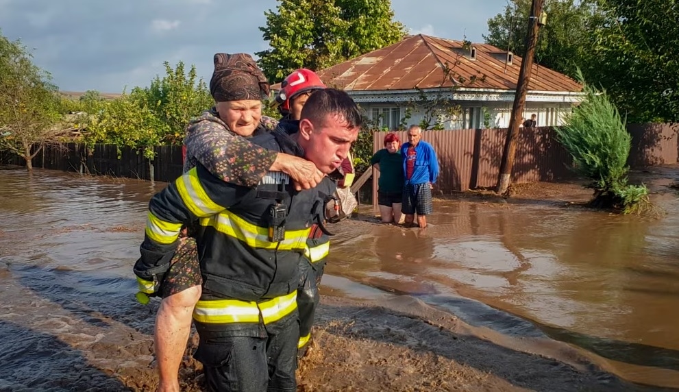 Một nhân viên cứu hộ đang cõng một người phụ nữ ở Pechea, Romania (Theo: AP)