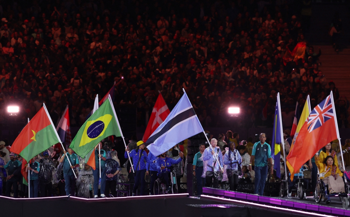 VĐV các đoàn thể thao tham dự diễu hành qua lễ đài với lá quốc kỳ (Ảnh: Reuters)