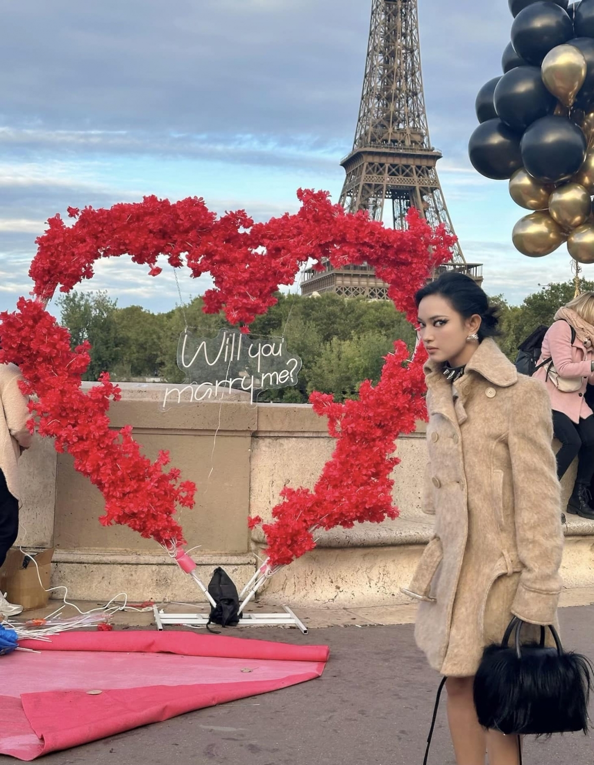 Châu Bùi đăng ảnh chụp ở Paris với biểu cảm hài hước, khung cảnh phía sau được trang trí bằng bóng bay, hoa kèm dòng chữ "Will you marry me?". Cộng đồng mạng cho rằng cô đang nhắc khéo Binz sớm cầu hôn. (Nguồn: FBNV)