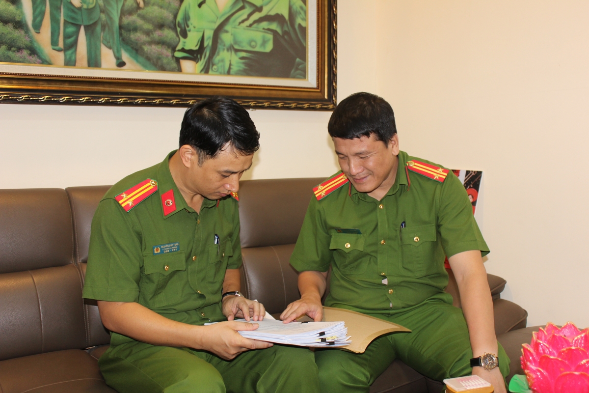 Trung tá Nguyễn Anh Tuấn (bên phải) trao đổi công việc với đồng nghiệp
